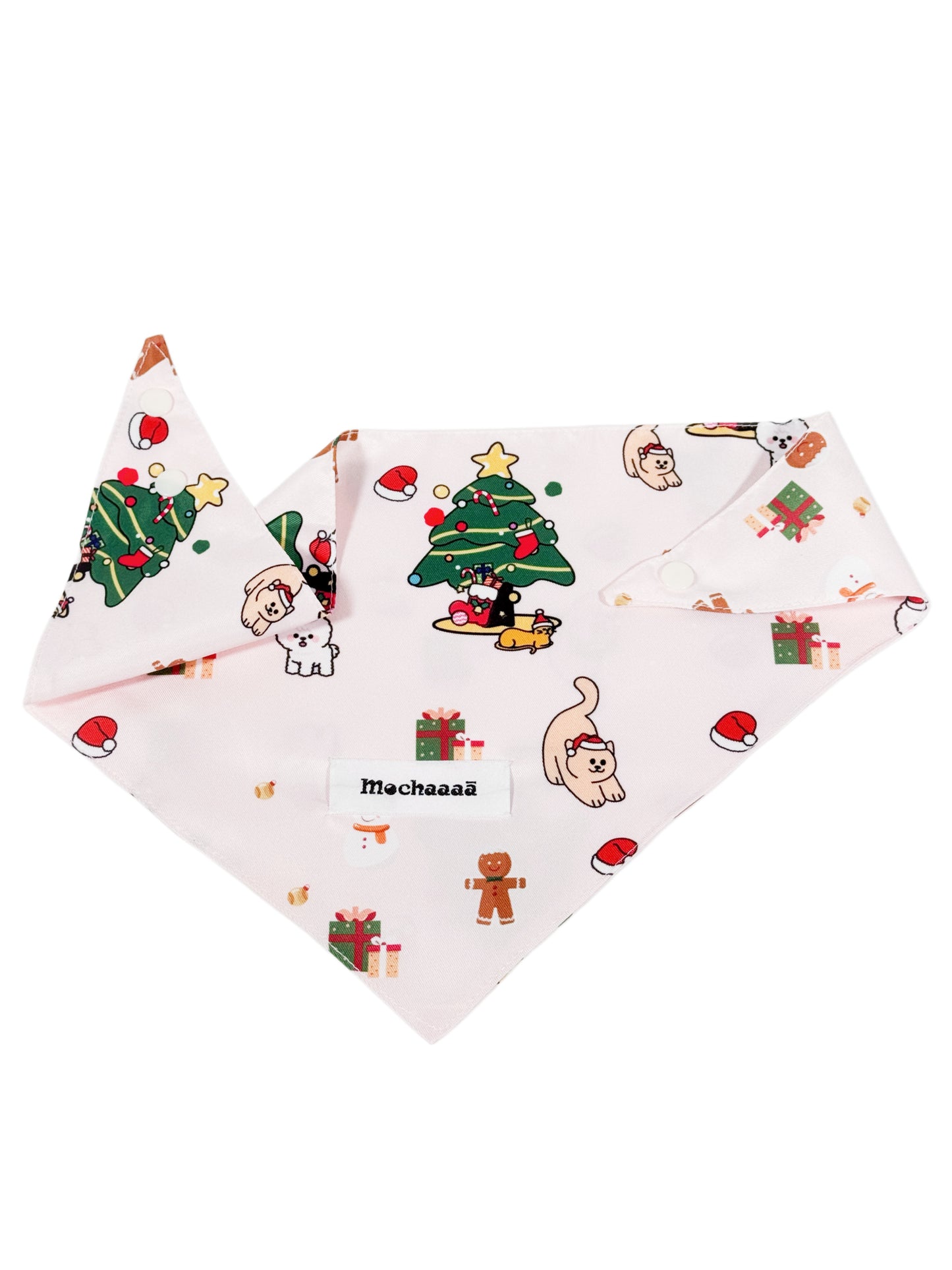 A light pink dog bandana featuring a festive Christmas print with cartoon cats, gingerbread men, Santa hats, and a Christmas tree. The bandana is displayed flat against a solid white background, with a white label in the center reading 'Mochaaaā'.