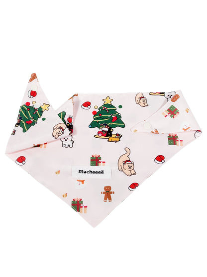 A light pink dog bandana featuring a festive Christmas print with cartoon cats, gingerbread men, Santa hats, and a Christmas tree. The bandana is displayed flat against a solid white background, with a white label in the center reading 'Mochaaaā'.