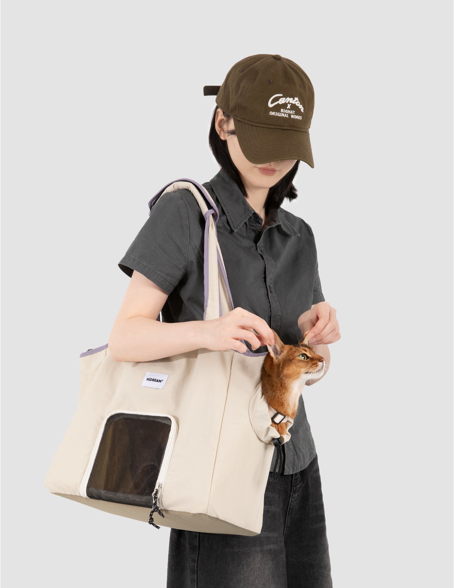 Person holding a small dog in a pet carrier bag against a plain background