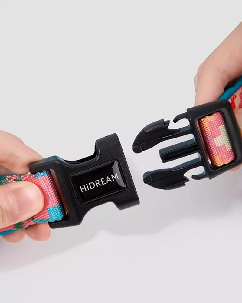Hands holding HIDREAM branded side-release buckle on colorful dog leash – secure quick-release design with durable nylon strap for easy attachment and removal