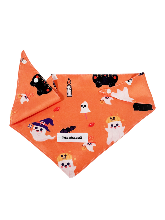 An orange pet bandana featuring a cute Halloween print with cartoon ghosts, witches, bats, pumpkins, and candles. The bandana is folded to show both the front patterned side and the reverse side with a white brand label that reads 'Mochaaaā'.