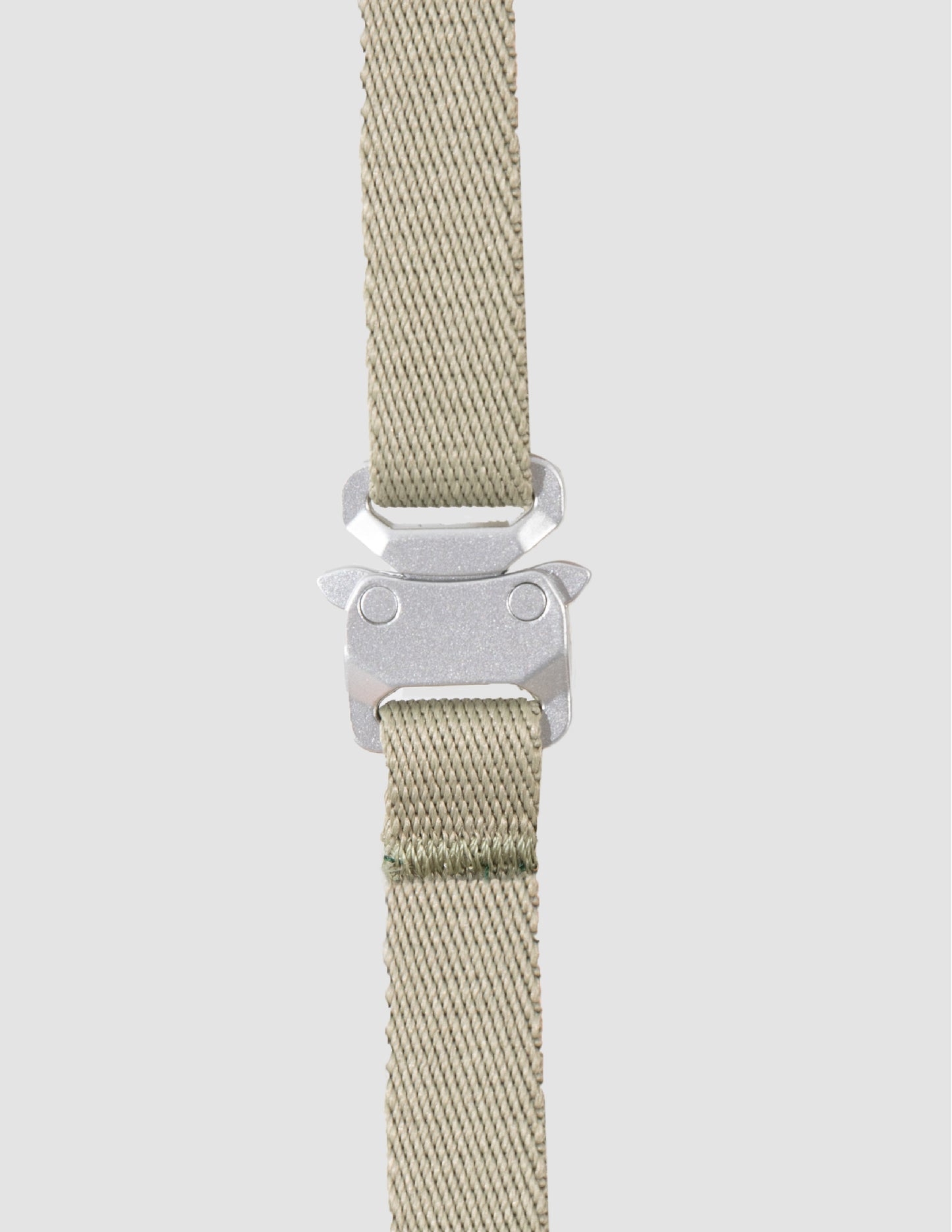 Beige woven strap with a silver buckle on a light gray background