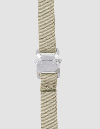 Beige woven strap with a silver buckle on a light gray background