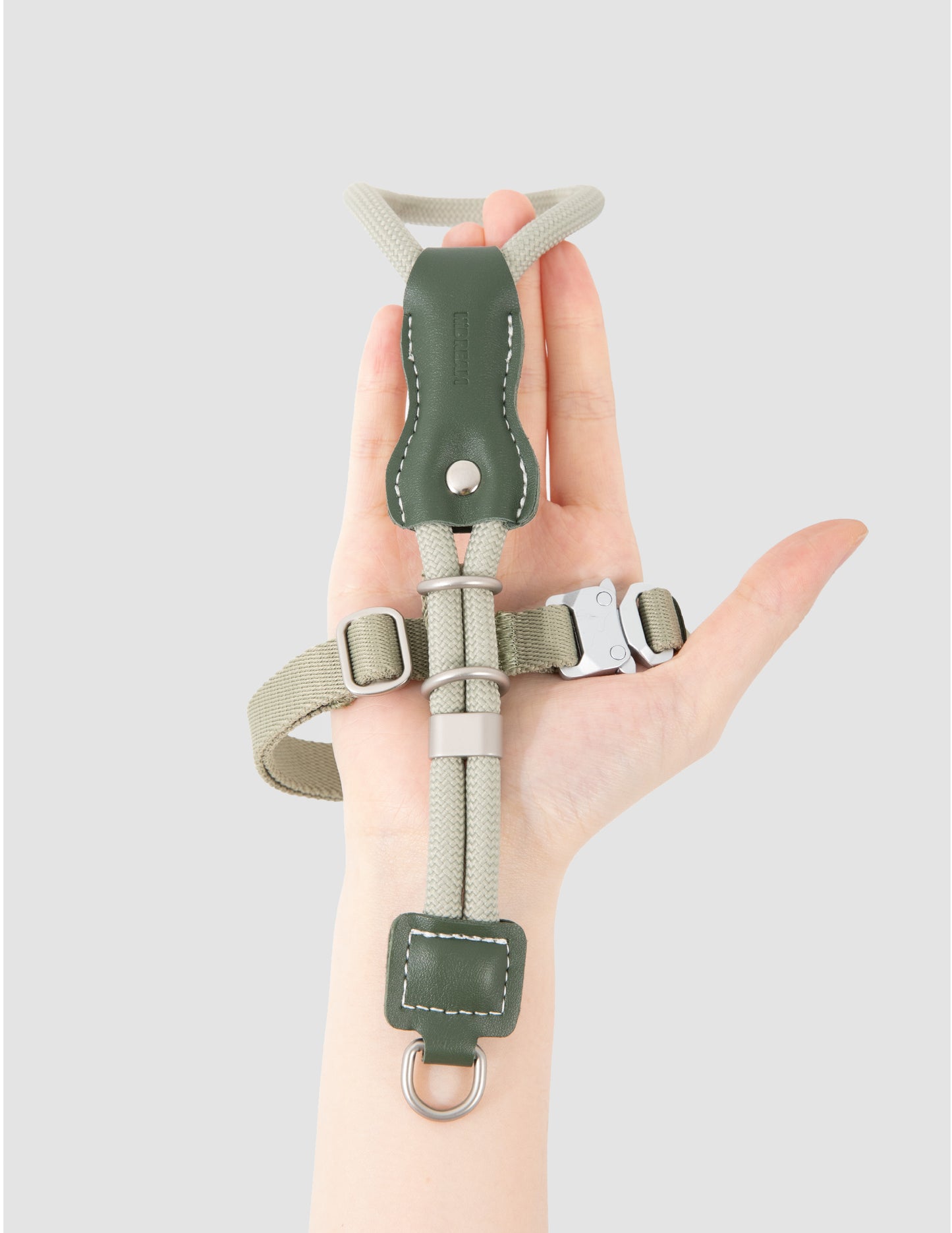 Hand holding a green and gray wrist support brace against a light gray background