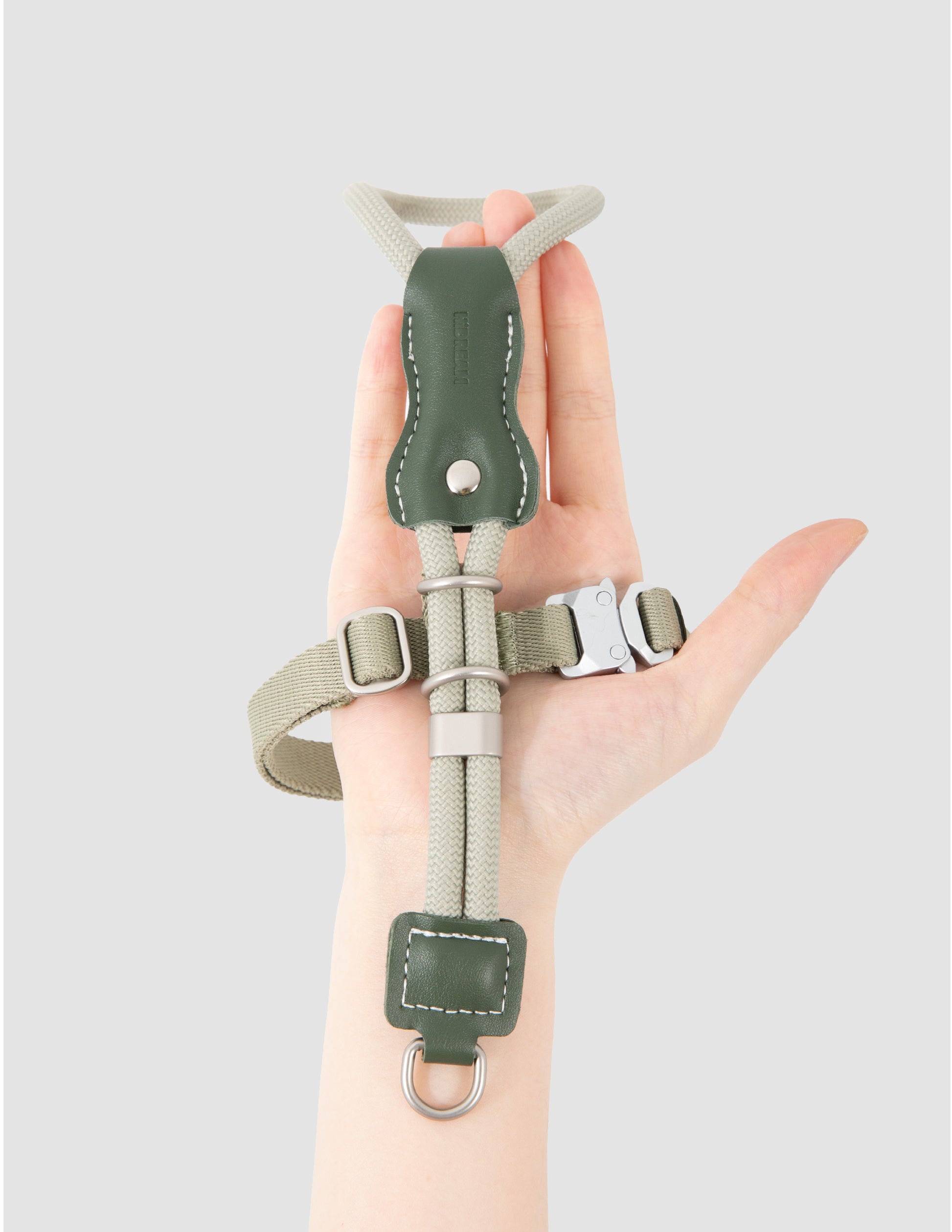 Hand holding a green and gray wrist support brace against a light gray background