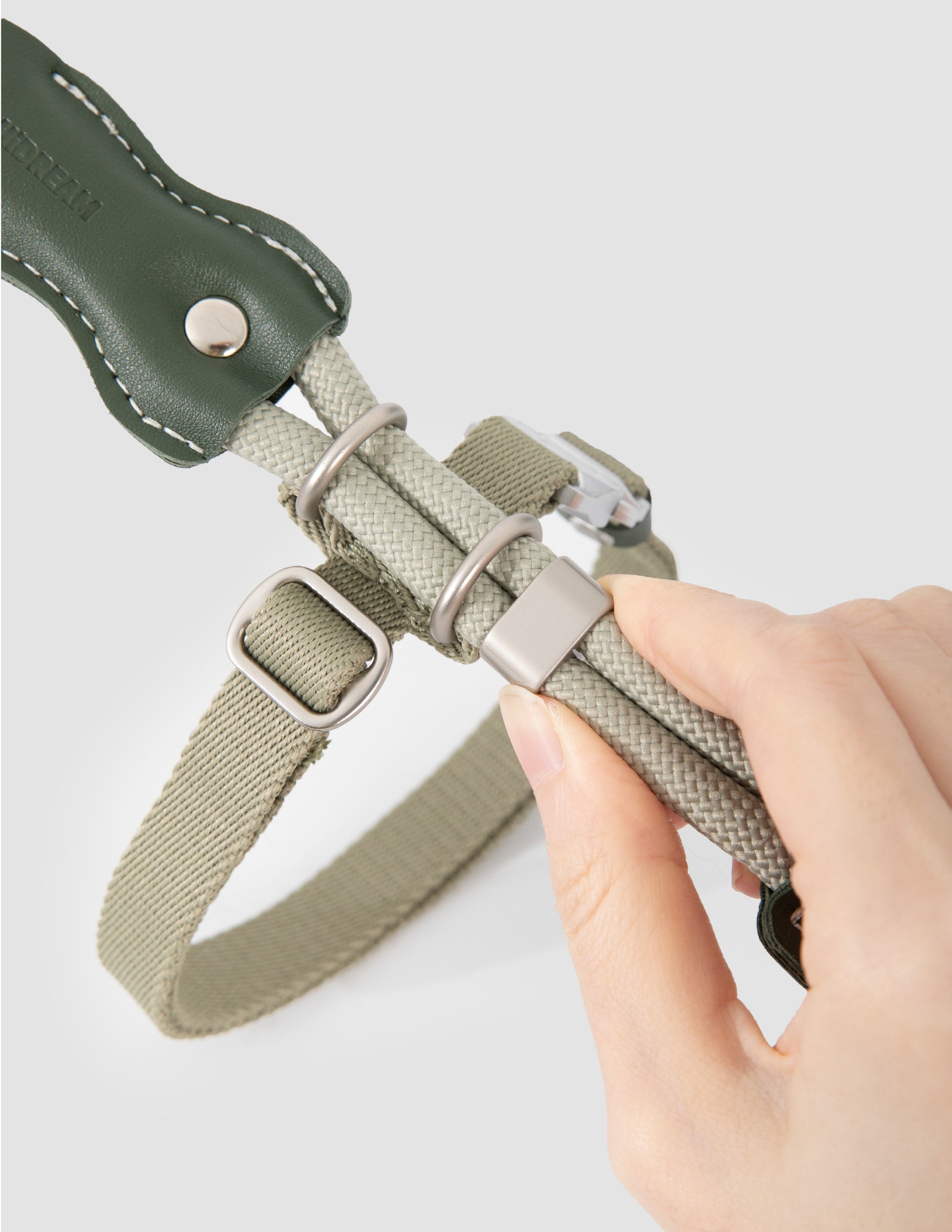 Hand holding a green cat collar with a white background